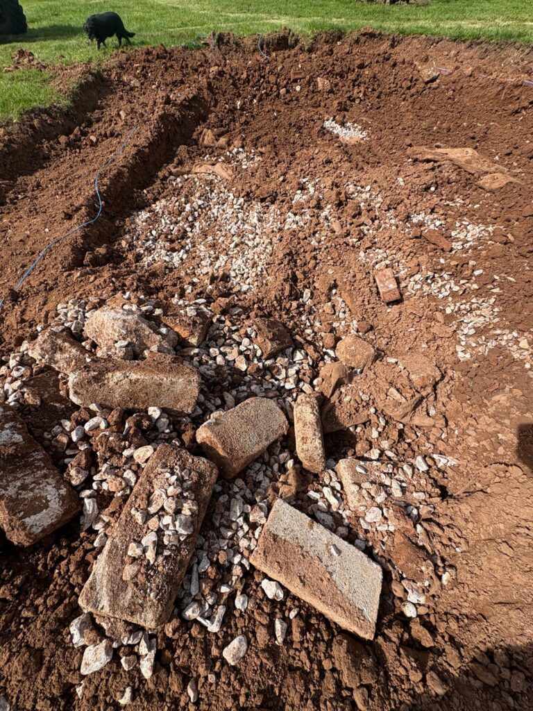 Discovery of buried soakaway and drainage material during wildlife pond excavation in Devon.