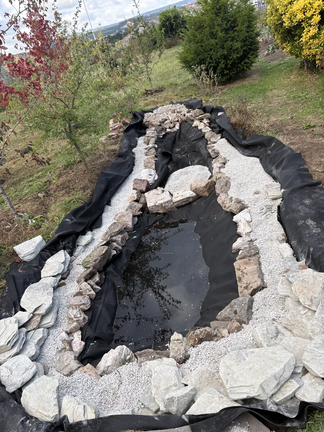 New pond liner with stone divisions defining the planted margins during construction